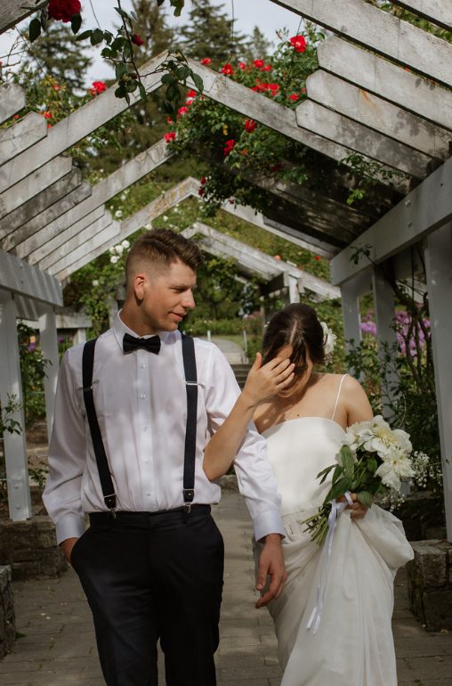 Couple walking under a rose-covered arbor